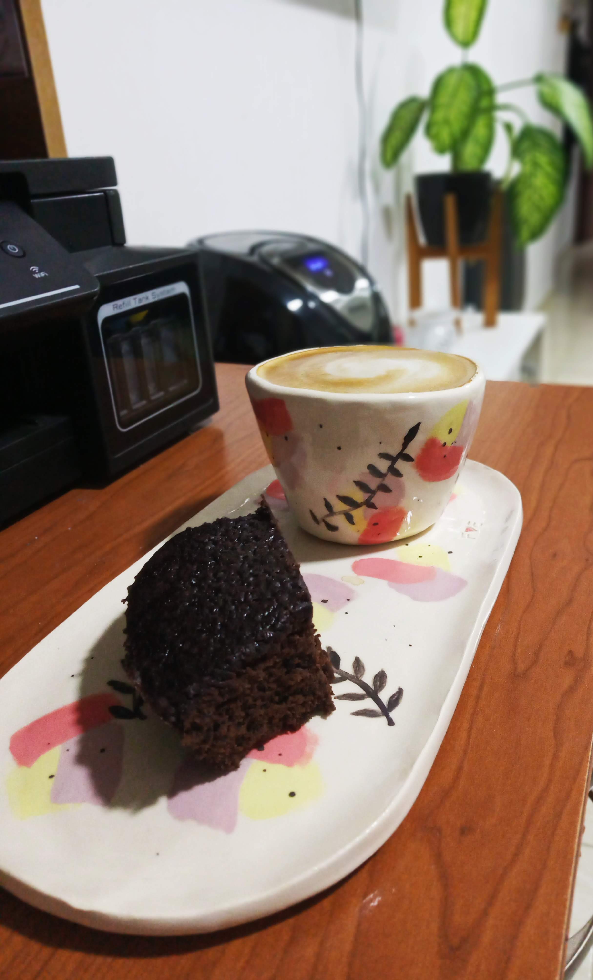 Set de bandeja mediana ovoide con taza sin aza, de fondo color hueso y decoración con engobe negro en forma de hojas pequeñas y manchas de colores amarillo, lila y coral pastel